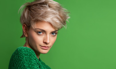 Portrait of young woman with blond short hair isoalted on green background
