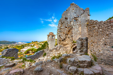 Fototapeta na wymiar Renovated tower clock among ruined wall with crack of citadel in a sunny summer day and clear sky as postcard, copy-space for text. Summer landscape in Fortress Old Bar Town, Montenegro.
