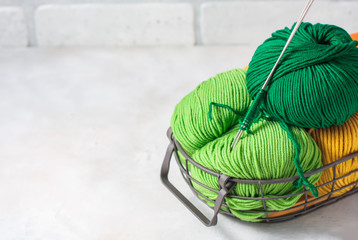 Different colored yarn in a basket with a knitting needle. The concept of knitting and needlework.