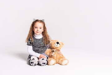A little girl with a bear standing on a white background