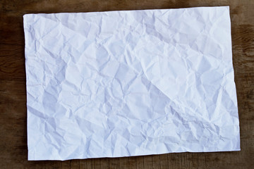 White crumpled paper on wooden background.