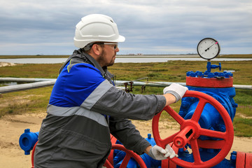 Oil, gas industry. Group wellheads and valve armature, gas production process, Gaz operator, The operator anneals the gas well with a torch.