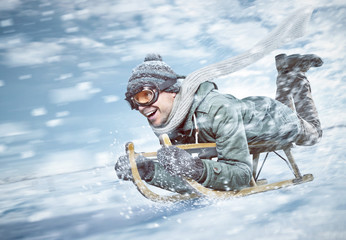 Mann in voller Fahrt beim Rodeln im Schnee