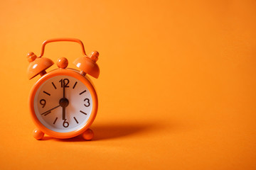 Analogue clock on orange background.