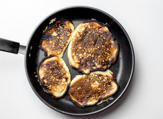 Cooking failed, burnt pancakes on a black pan.