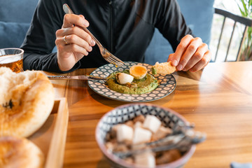 Close-up of a man having lunch. Hummus with nuts and boiled egg and olive oil. It is served in the Oriental restaurant. With wheat cake. Healthy, organic food. traditional israeli cuisine