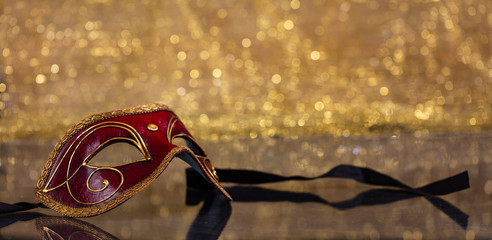 Carnival mask on golden bokeh background, copy space