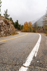 A curvy mountain road rounds orange lined fall colored cliffs
