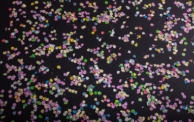 Fototapeta na wymiar Carnival or birthday party, confetti on black background