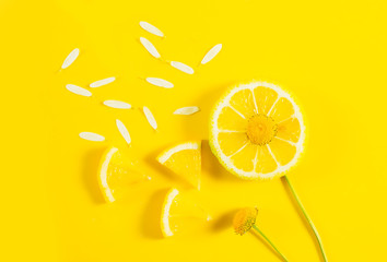 Lemon, chamomile and petals on a yellow background. The minimal concept of summer, diet, lightness, good mood
