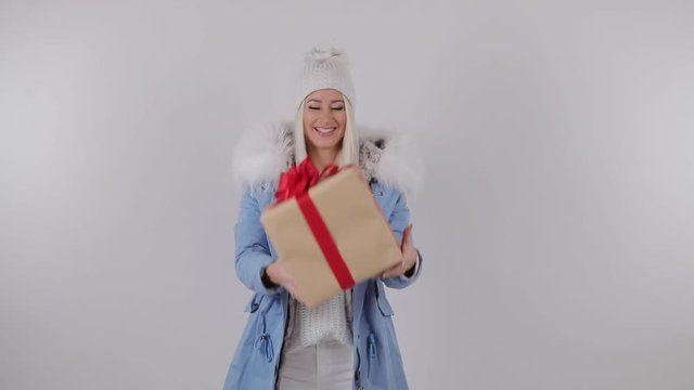 Happy Amazed Woman in winter fur coat, Holding Present in Her Hands, makes a wish and gets a gift box. White background. 4k slow motion video