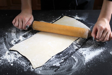 Woman preparing buns from puff pastryat table in bakery. The cook preparing buns at table in...