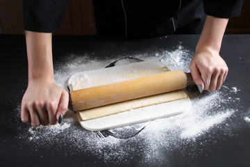 Woman preparing buns from puff pastryat table in bakery. The cook preparing buns at table in...