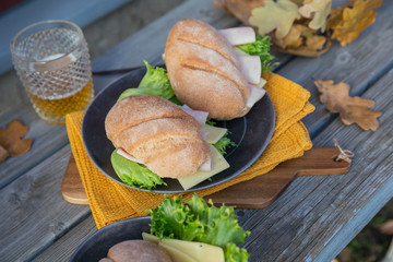 Ciabatta baguette sandwiches with ham, cheese, lettuce and a glass of beer