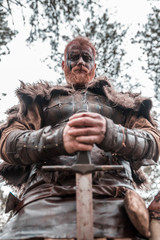 Fototapeta na wymiar viking with red beard with armor shield and sword in the battle field