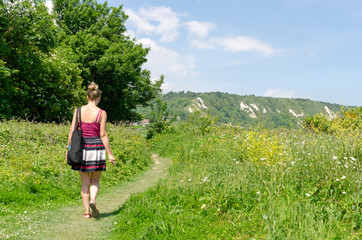 Woman walking in the English countryside towards the White Cliffs in summer, Dover