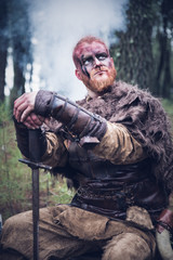 Obraz premium viking with red beard with armor shield and sword in the battle field