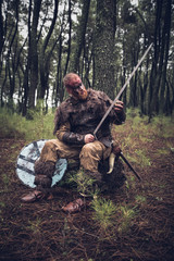 viking with red beard with armor shield and sword in the battle field