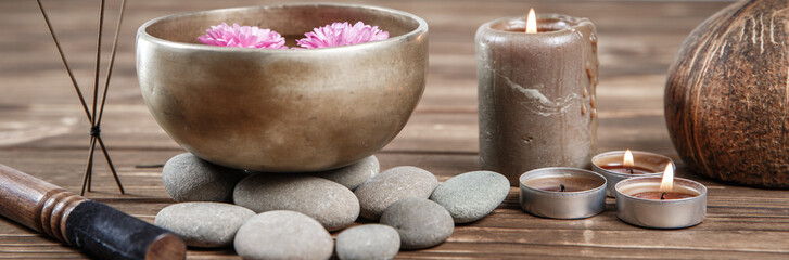 Singing bowl with candles with pebbles on dark wooden background
