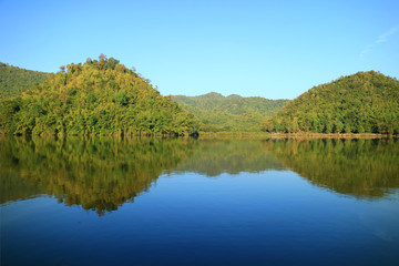 Fototapeta na wymiar Stunning view of the reflections of mountains on Hoob Khao Wong Reservoir, Suphanburi province, Thailand