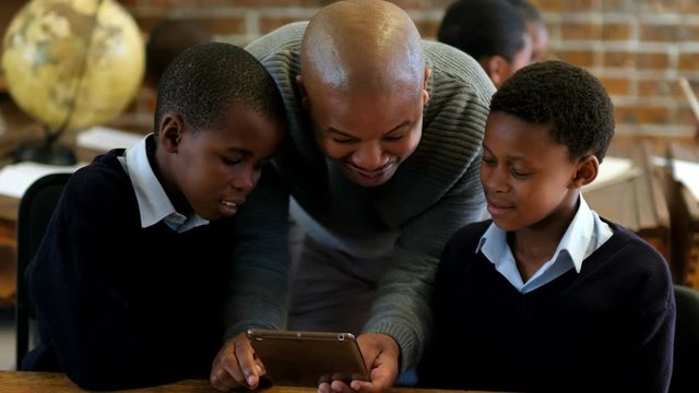 Male teacher using digital tablet with students in classroom 4k