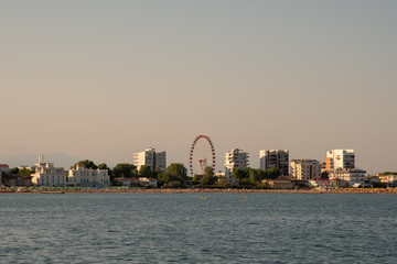 Fototapeta premium Coast city with ferris wheel and skyscrapers at sunset, Jesolo Lido, Venice, Italy