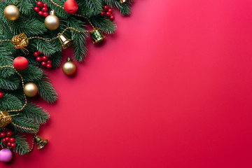 Christmas background concept. Top view of Christmas with spruce branches, pine cones, red berries and bell on red background.