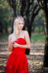 Portrait of princess in crown and red dress in forest © Elina Leonova