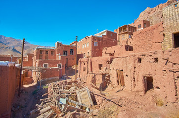 The rubbish dump in old street of Abyaneh mountain village with preserved medieval houses and abandoned buildings around it, Iran.