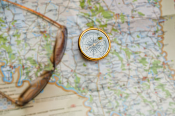 Close-up photo of compass laying on the map next to the sunglasses.