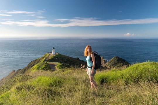Woman stands in front of lighthouse at Cape Reinga, Northland, North Island, New Zealand, Oceania