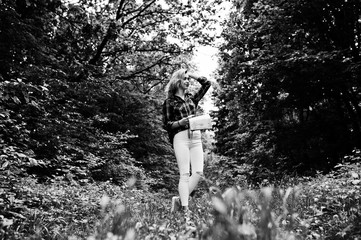 Portrait of a young beautiful blond woman in tartan shirt holding a map in the forest.