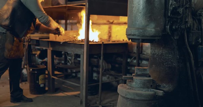 Blacksmith gets a horseshoe from the furnace. Blacksmith stamps horseshoe