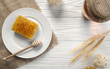 Honey comb on white plate and glass jar on wooden background