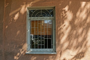 window with gray iron grill on brown concrete wall