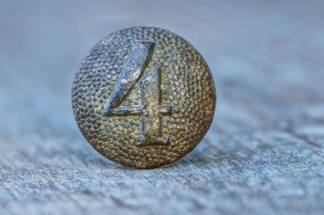 old gray button with the number four on a wooden table