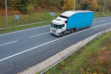 Articulated lorry with blue high double decker trailer in motion on the road
