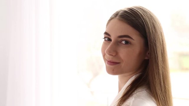 Young woman looking at window then turning head to gaze at camera indoors
