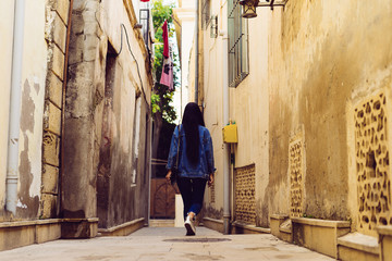 girl with long black hair walks the old streets of Baku city in Azerbaijan, likes to travel