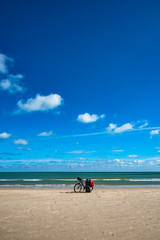 Fototapeta na wymiar Lonely bike with loaded backpack of a traveler on oceanic beach with blue sky and sunny day, summer time
