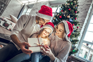 It's time to Christmas magic. Happy family looking inside of magic Christmas gift box.