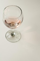 Transparent glass of wine. Pink wine. Festive mood. Alcohol for a group of friends. Delicious drink. Light background. Noble drink. Lavender and rose wine. Wine from lavender