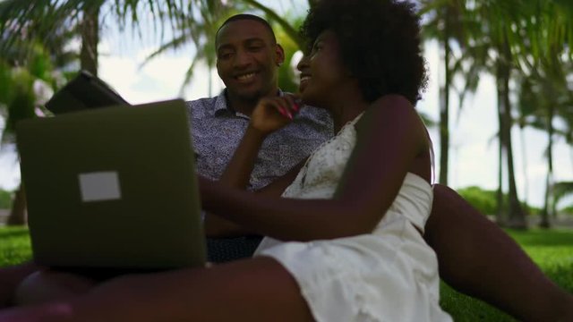 Young Black Couple Using Technology in the Park. Laptop, Tablet, phone. Miami beach Florida US