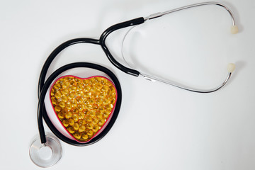 A heart-shaped box with tablets inside and a stethoscope. Medical concept, care for the heart,...