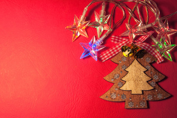 Flat wooden christmas tree and lights led garland on red paper background. Top view.