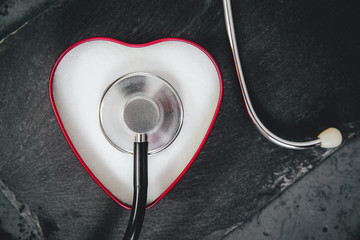 Heart-shaped box filled with white kitchen salt and a stethoscope. Medical concept, care for the...