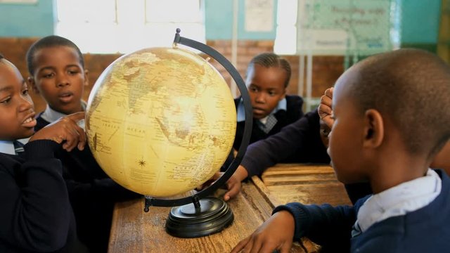 African American schoolkids using globe in classroom 4k