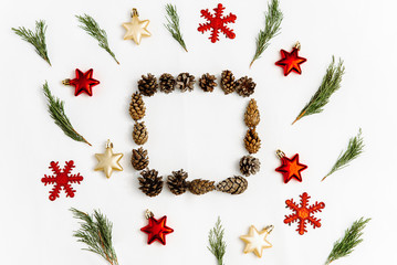 Christmas frame made from cones on a white background. Christmas composition of different Christmas toys and small branches of spruce. Top view, flat lay, copy space