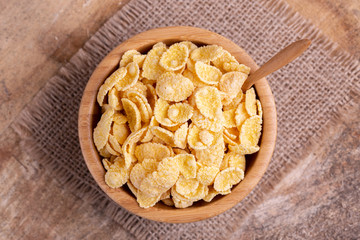 Crunchy corn flakes in wooden bowl with burlap napkin