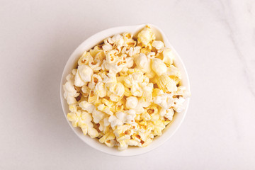 Tasty salty popcorn in bowl on light marble backgraund